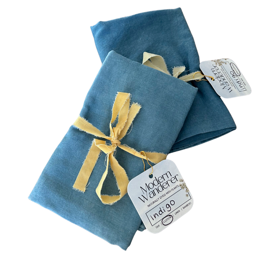 Two blue bandanas with a yellow ribbon and 'Modern Wanderer' tag on a white background.
Naturally dyed with indigo.