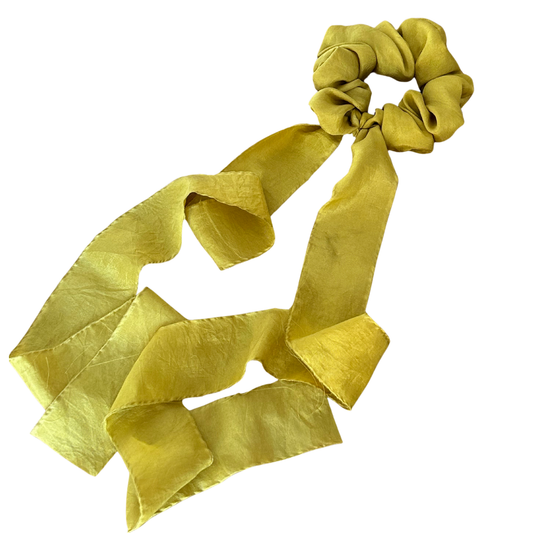 Green scrunchie with long ribbon on white background. Naturally dyed with marigolds.